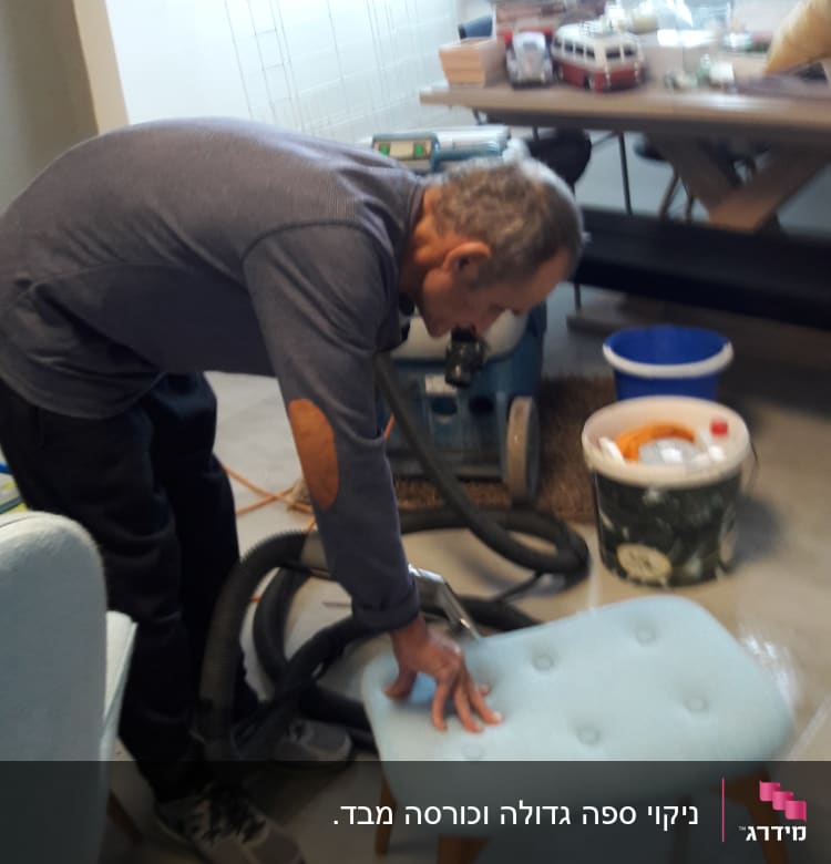 אדם מנקה כיסא עם שואב אבק